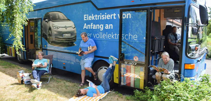 viele Leserinnen und Leser tummeln sich im Grünen und den Bücherbus herum